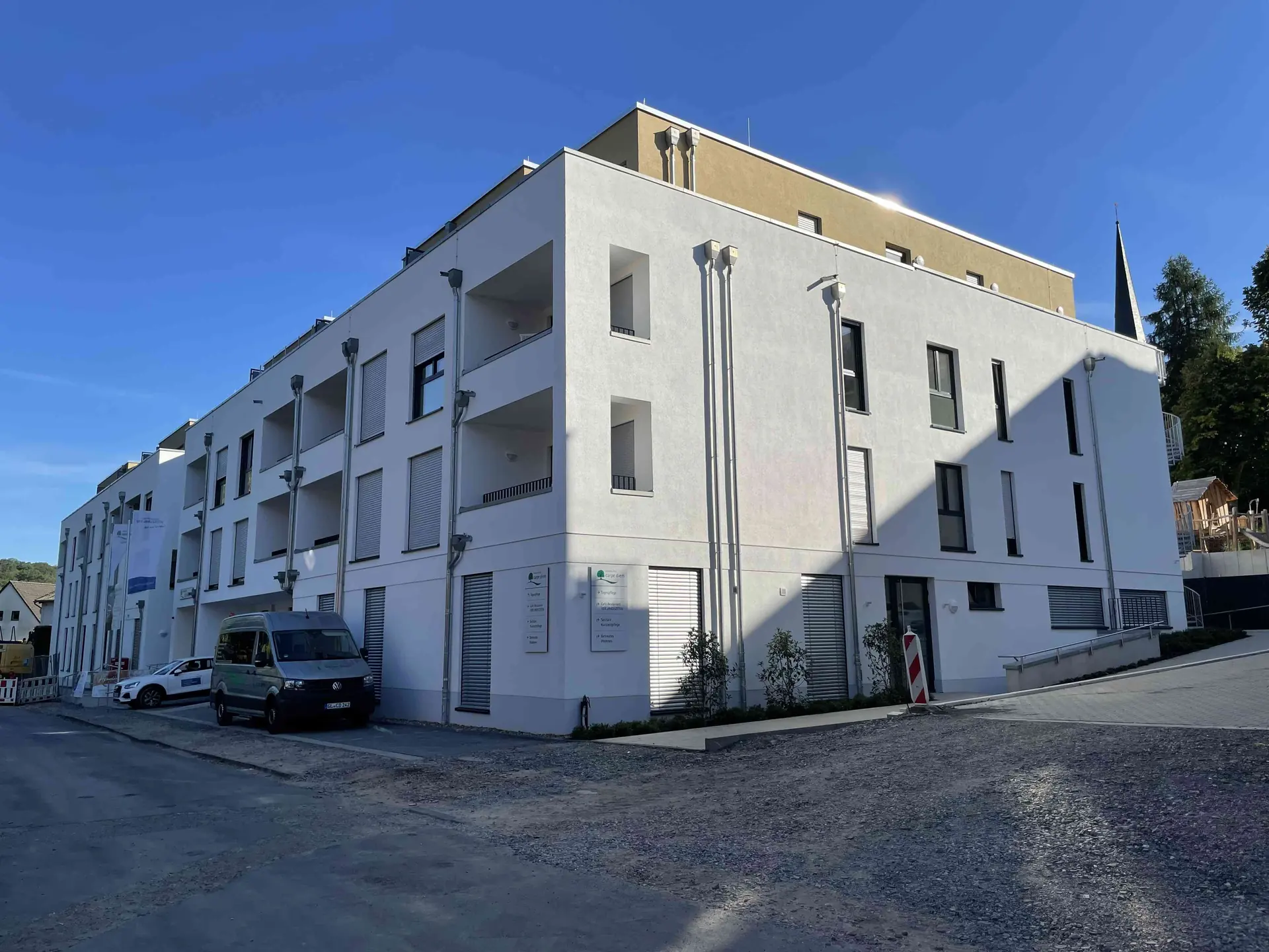 Das fertiggestellte Vital Quartier Much mit weißer Fassade, Balkonen und Eingangsbereich
